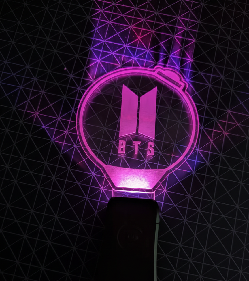 BTS ARMY Bomb lightstick glowing purple with the BTS logo inside a transparent globe against a geometric dark background.
