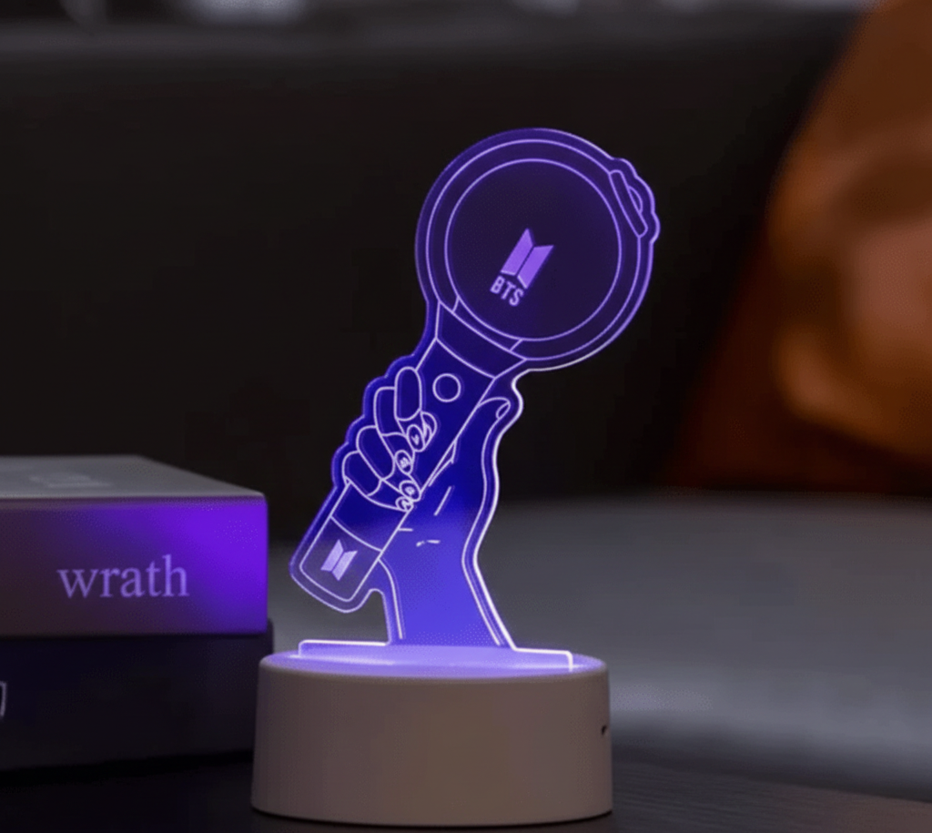 A glowing acrylic BTS lightstick lamp shaped like a hand holding the ARMY Bomb, lit in soft purple on a small round base.