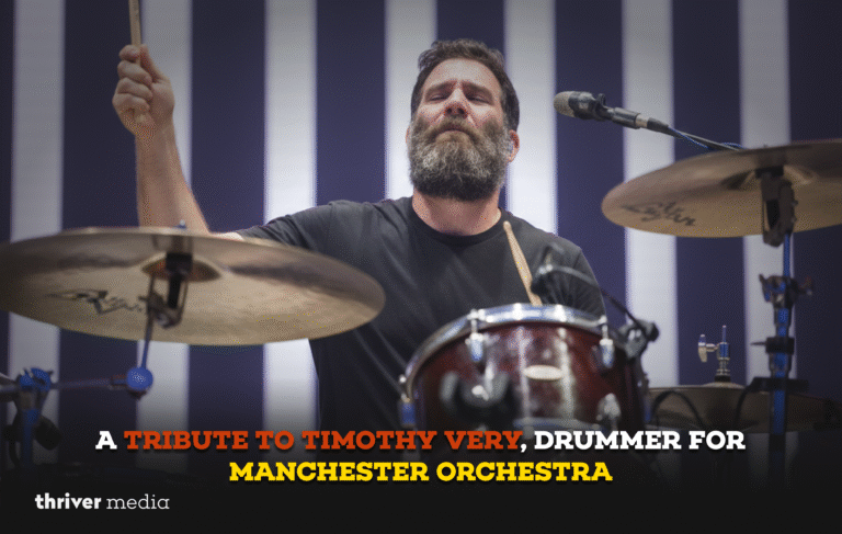 Bearded drummer performing on stage with raised drumstick, tribute graphic reading “A Tribute to Timothy Very, Drummer for Manchester Orchestra.”