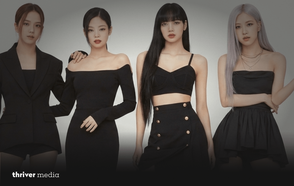 BLACKPINK members pose together in elegant black outfits against a neutral studio background.