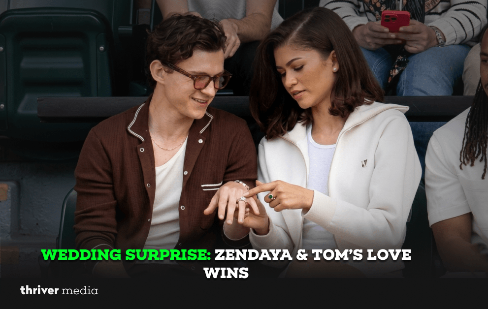 Zendaya pointing at a ring on Tom Holland’s finger as they sit together smiling at a public event.