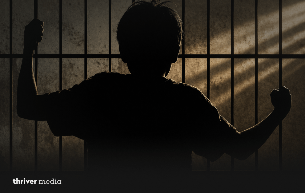 5 Brutal Truths: Who Is Responsible for Child Crime 2 Silhouette of a child holding prison bars in a dark setting, symbolizing juvenile crime and confinement.